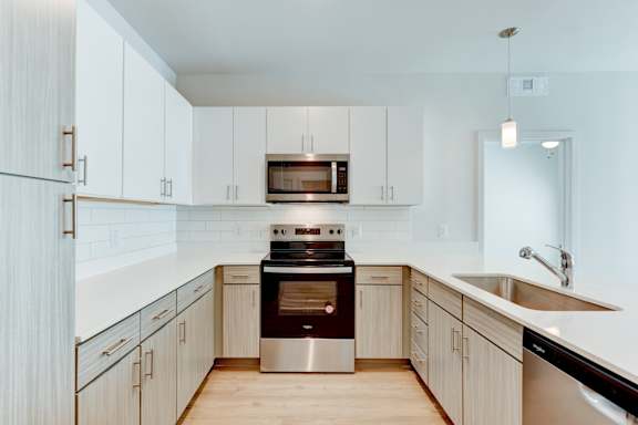 A modern kitchen with a stainless steel oven and white cabinets. at Park South Apartments, Austin, TX