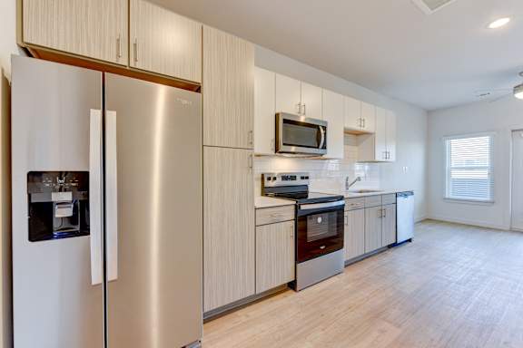 A modern kitchen with a stainless steel refrigerator and wooden cabinets. at Park South Apartments, Texas, 78748