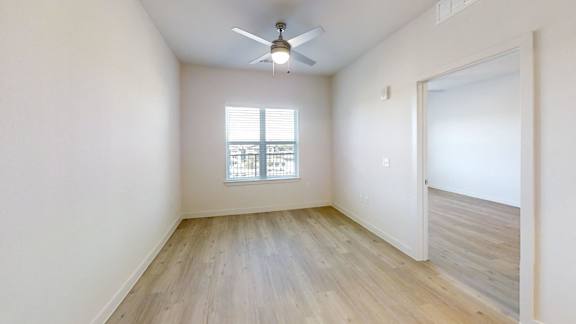 A room with a ceiling fan and a window with blinds.