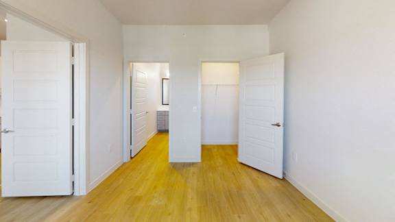 A hallway with white doors and a wooden floor.