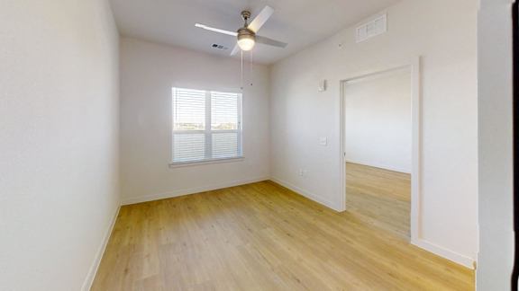 A room with a ceiling fan and a window with blinds.