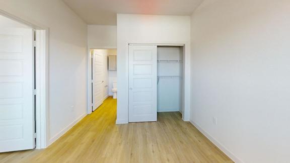 A room with white walls and wooden flooring with two white doors.