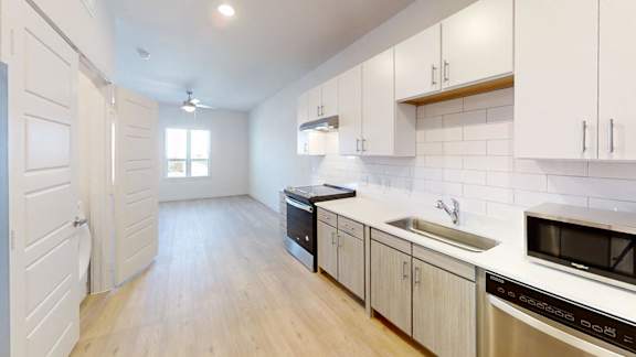 A kitchen with white cabinets and a wooden floor.