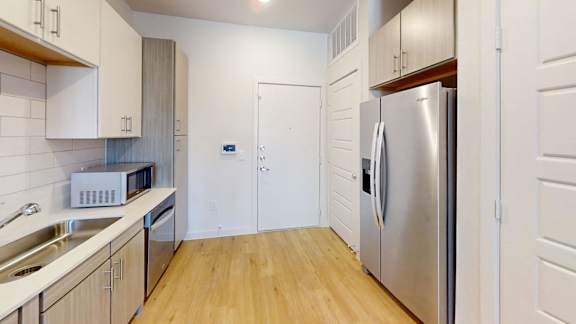 A kitchen with a refrigerator, sink, and microwave.