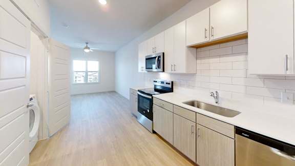 A kitchen with white cabinets and a wooden floor.