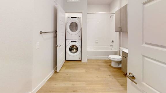 A white bathroom with a washer and dryer in the doorway. at Park South Apartments, Austin