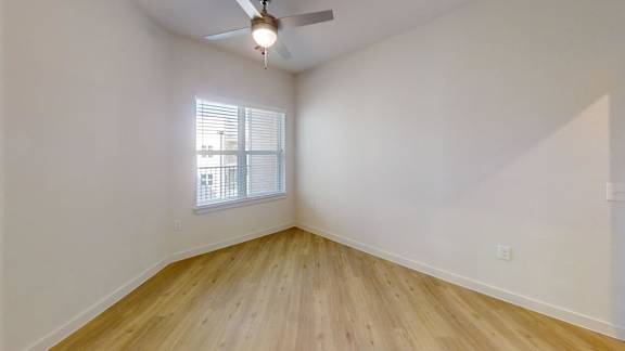 A room with wooden flooring and a window with blinds. at Park South Apartments, Austin, Texas