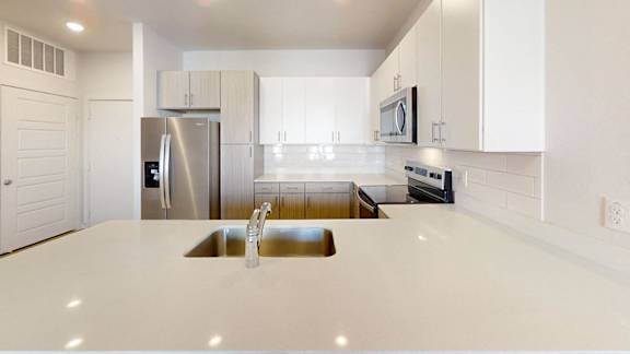 A modern kitchen with a stainless steel refrigerator and white cabinets. at Park South Apartments, Austin, TX
