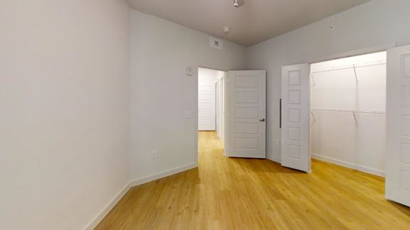 A room with white walls and wooden flooring with three doors at Park South Apartments, Austin, Texas