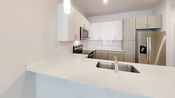 A modern kitchen with a stainless steel refrigerator and a white countertop. at Park South Apartments, Texas