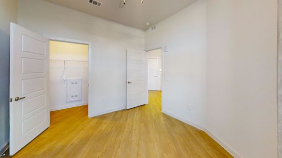 A room with white walls and wooden flooring with three doors. at Park South Apartments, Austin