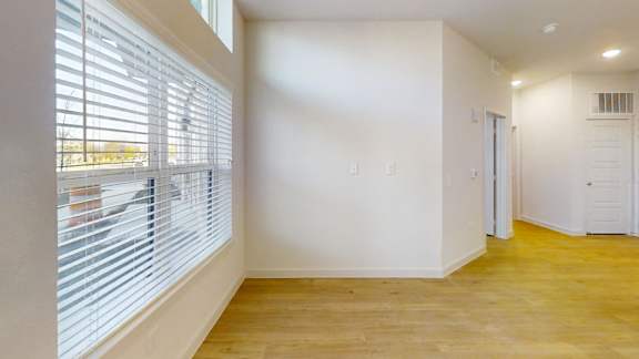 A room with a window covered by blinds and a wooden floor. at Park South Apartments, Austin, TX