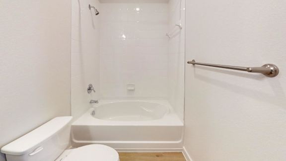 A white toilet sits next to a bathtub in a bathroom.