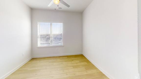 A room with a ceiling fan and a window with blinds.