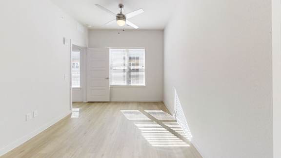 A room with a ceiling fan and a window with blinds.
