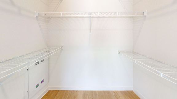 A white walk-in closet with a white door and shelves.