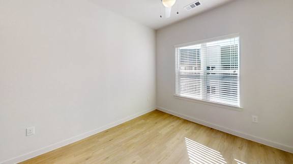 A room with wooden flooring and a window with blinds.