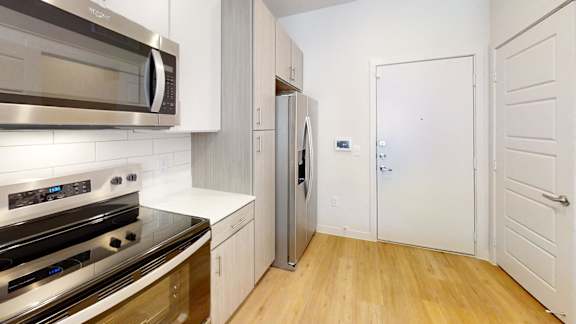 A kitchen with a stove, microwave, and refrigerator.