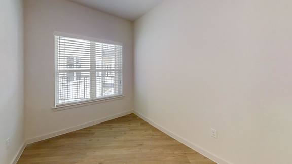 A room with a window and wooden flooring. at Park South Apartments, Texas
