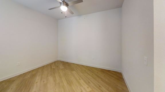 A room with a ceiling fan and wooden flooring. at Park South Apartments, Austin