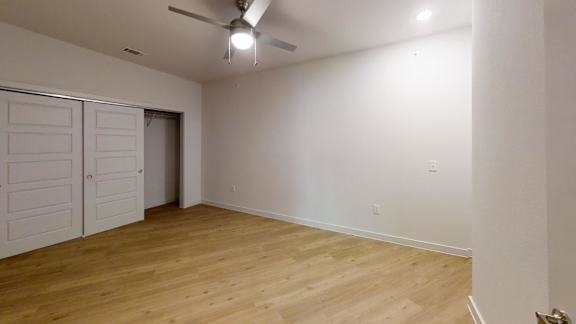 A room with a ceiling fan and wooden flooring. at Park South Apartments, Austin, Texas