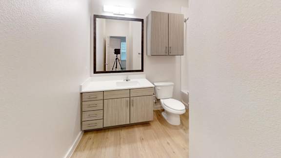 A bathroom with a toilet, sink, and a mirror. at Park South Apartments, Austin, TX