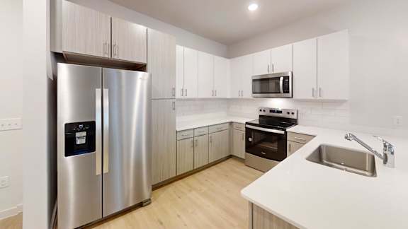 A modern kitchen with a stainless steel refrigerator and white countertops. at Park South Apartments, Austin