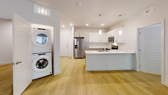 A modern laundry room with a washer and dryer built into the cabinetry. at Park South Apartments, Austin, Texas