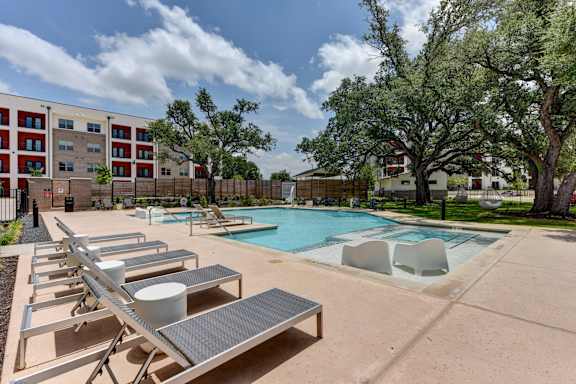 A pool with sun loungers and a building in the background.