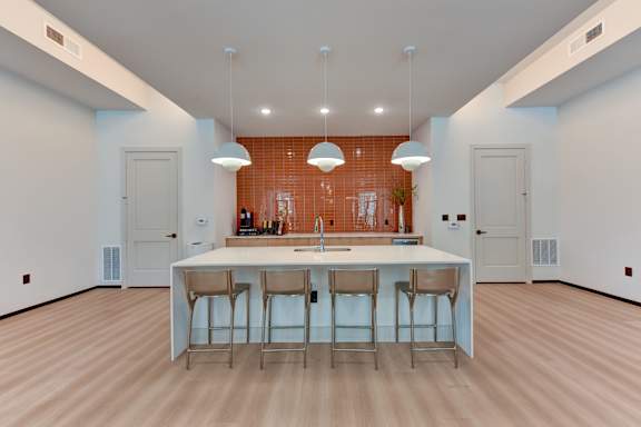 A kitchen with a bar area and four stools.