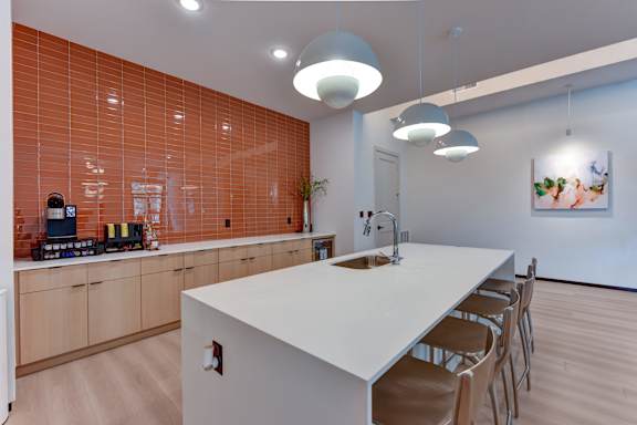 A kitchen with a white counter and orange tiles on the wall.