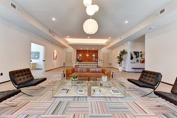 A living room with a multicolored carpet and a glass coffee table.