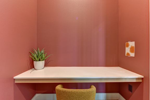 A white desk with a plant and a picture on the wall.