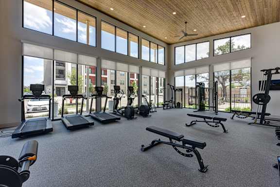 A gym with treadmills, elliptical machines, and weights.