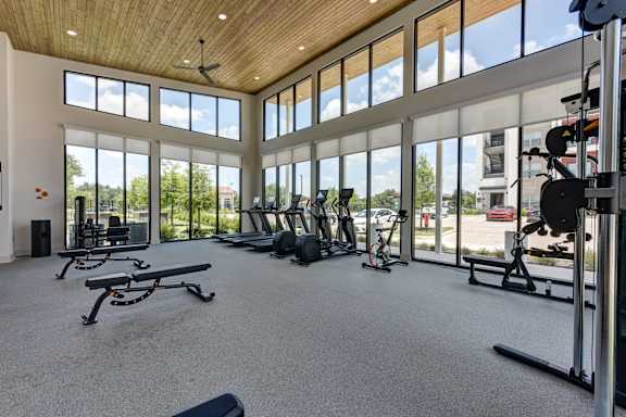 A gym with a variety of equipment and a view of the outside.