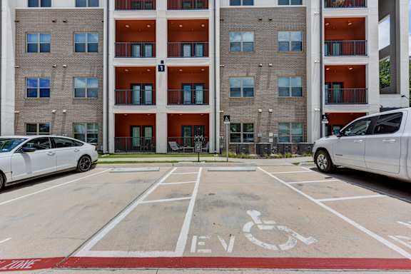 A parking lot with a white van and a red and white handicap sign.