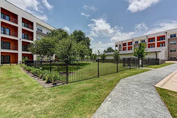 A black fence surrounds a grassy area in front of a building.