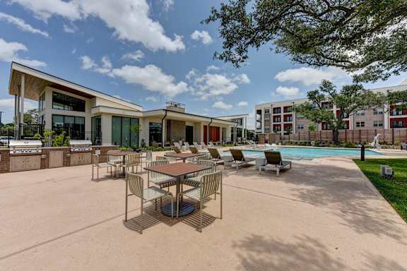 A pool area with a table and chairs in front of a building.