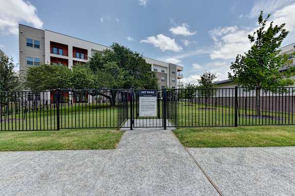 A black metal fence surrounds a plaque in front of a building.