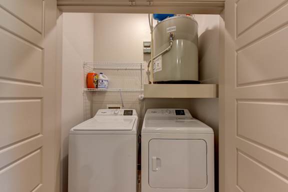 Laundry room with washer dryer and water heater at Bridge at Saffron Apartments, Texas