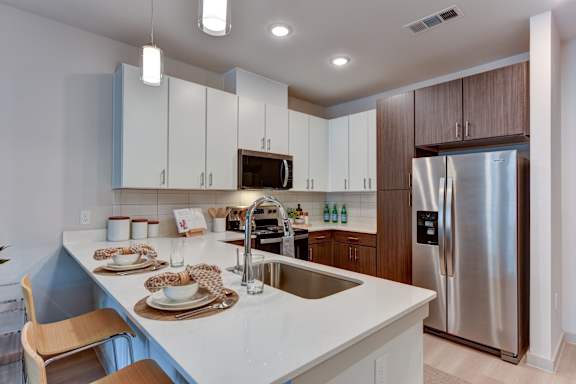 Kitchen island with sink and breakfast bar seating at Bridge at Saffron Apartments, Austin, TX 78717