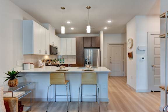 Kitchen island with bar seating and pendant lights at Bridge at Saffron Apartments, Austin, TX