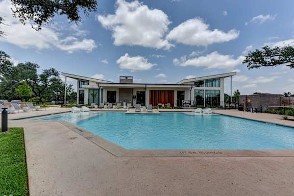 A large swimming pool in front of a modern house.