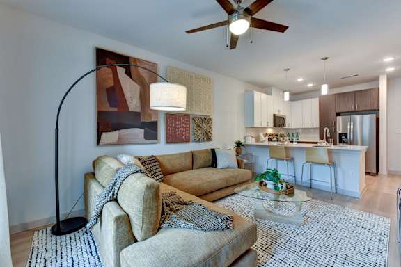 Open concept living room with sectional sofa and kitchen at Bridge at Saffron Apartments, Austin, Texas