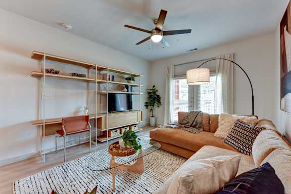 Living room with sectional sofa and modular shelving at Bridge at Saffron Apartments, Austin