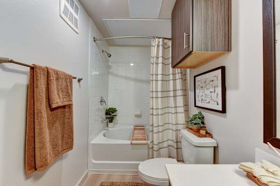 Bathroom with tiled tub shower and striped curtain at Bridge at Saffron Apartments, Texas, 78717