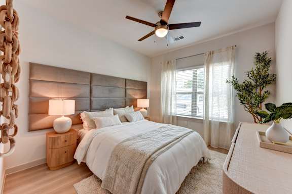 Bedroom with upholstered headboard and modern furnishings at Bridge at Saffron Apartments, Austin, TX 78717