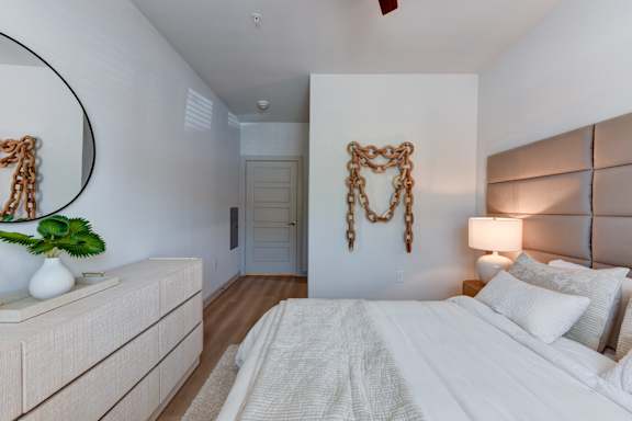 Modern bedroom with decorative chain wall art at Bridge at Saffron Apartments, Austin, Texas