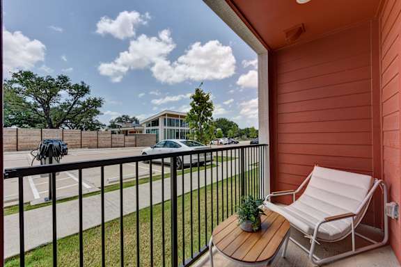 Balcony with seating overlooking parking and neighborhood at Bridge at Saffron Apartments, Texas
