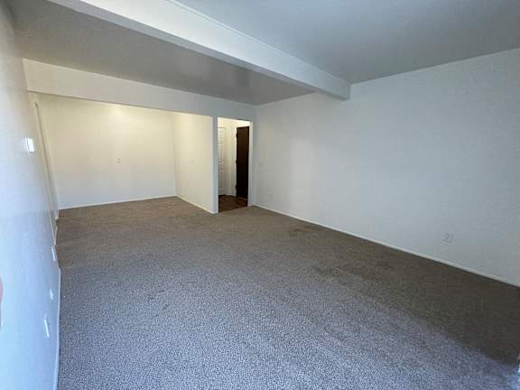 A living room with a carpeted floor and white walls.